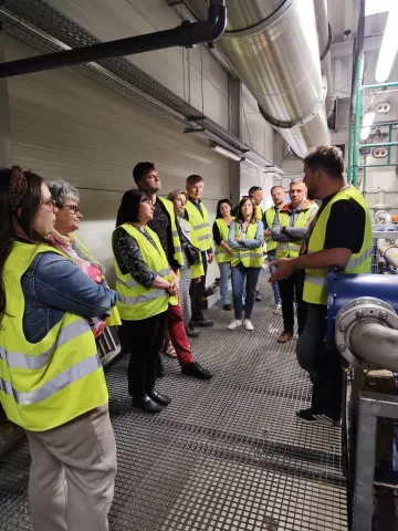 ludzie w kamizelkach odblaskowych w sortowni odpadów